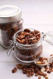 Photo of Jars with tasty granola on white wooden table, closeup