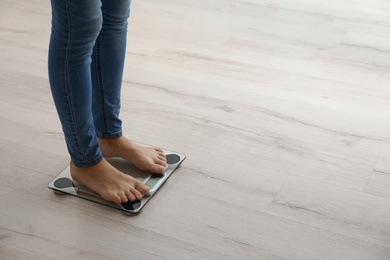Photo of Woman measuring her weight using scales on wooden floor. Healthy diet