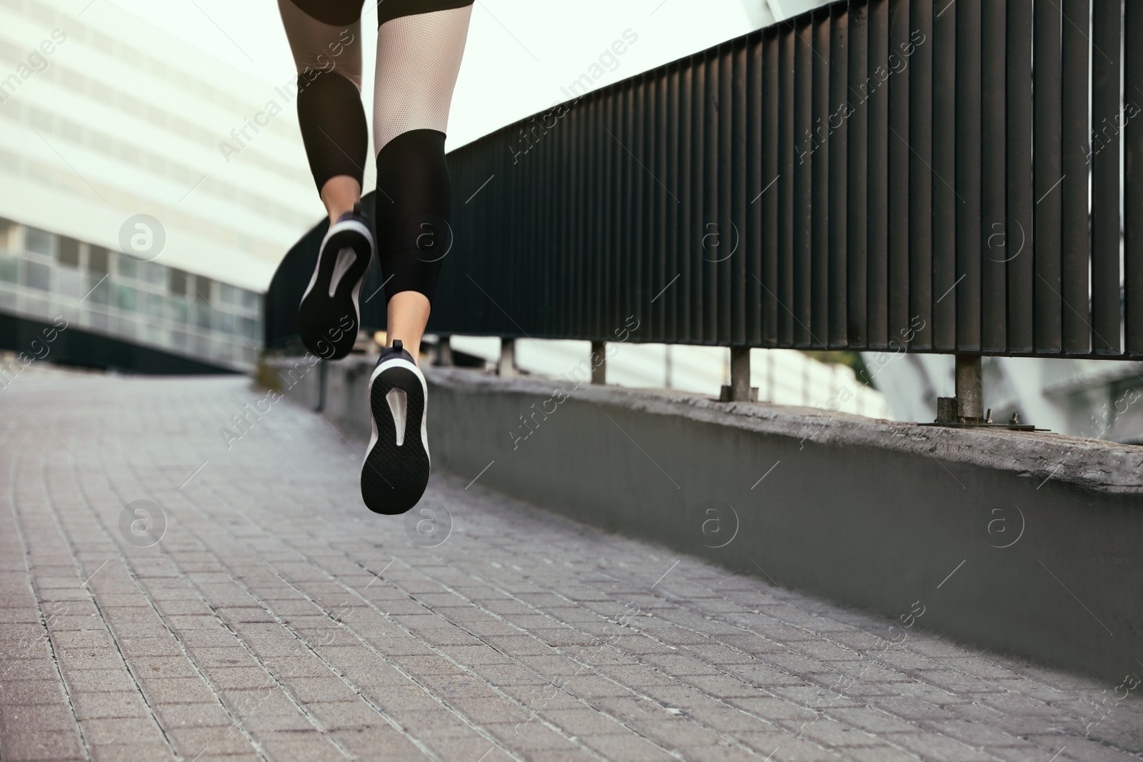 Photo of Beautiful sporty young woman running on street, closeup