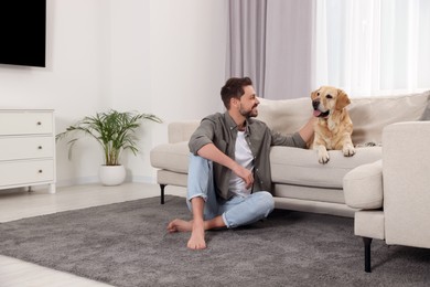 Photo of Happy man with his cute Labrador Retriever at home. Space for text