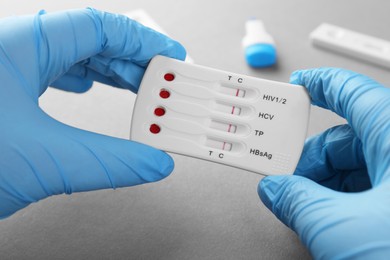 Photo of Doctor holding disposable multi-infection express test on light grey background, closeup