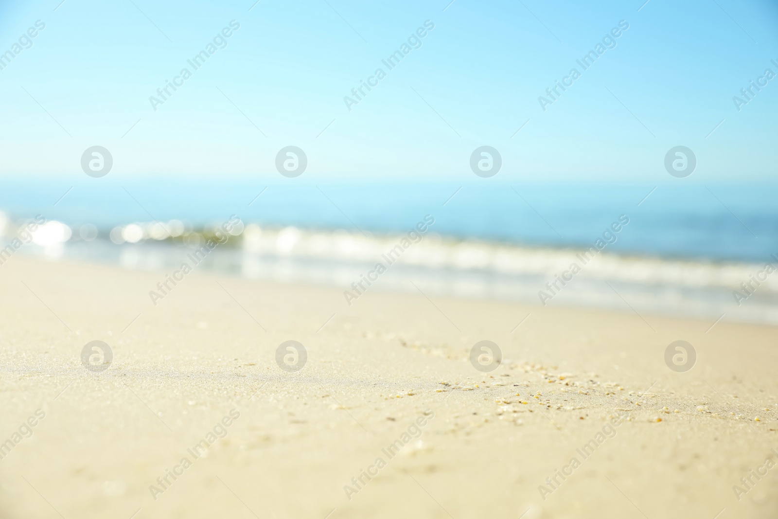 Photo of Beautiful sandy beach and sea under blue sky, closeup