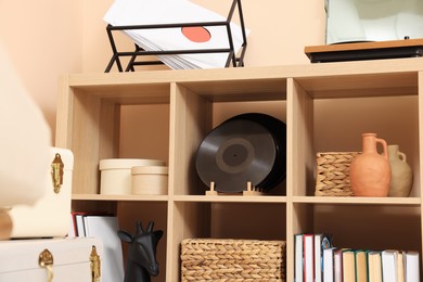 Wooden shelving unit with vinyl records near beige wall indoors