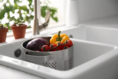 Colander pot with fresh vegetables in kitchen sink