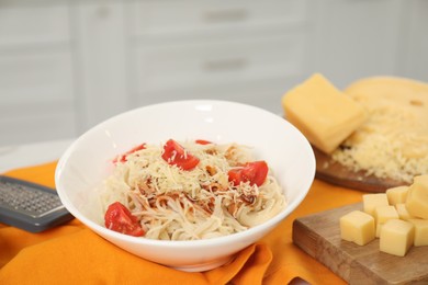 Photo of Delicious pasta with grated cheese and tomatoes on table indoors