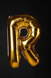 Photo of Golden letter R balloon on black background