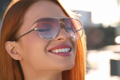 Beautiful smiling woman in sunglasses outdoors, closeup. Space for text