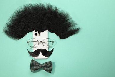 Flat lay composition with artificial moustache and glasses on turquoise background, space for text