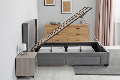 Photo of Comfortable bed with storage space for bedding under lifted slatted base in stylish room