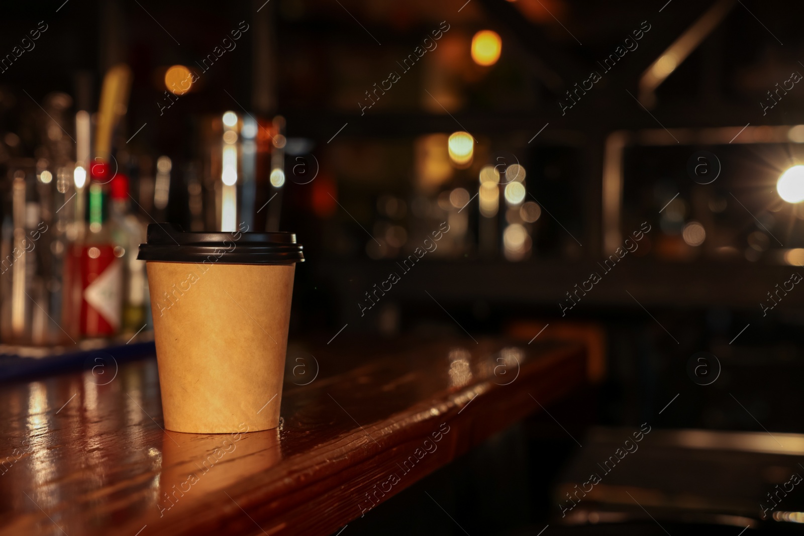 Photo of Paper coffee cup on wooden table in cafe. Space for text