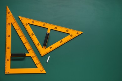 Triangles and chalk on green chalkboard, flat lay. Space for text