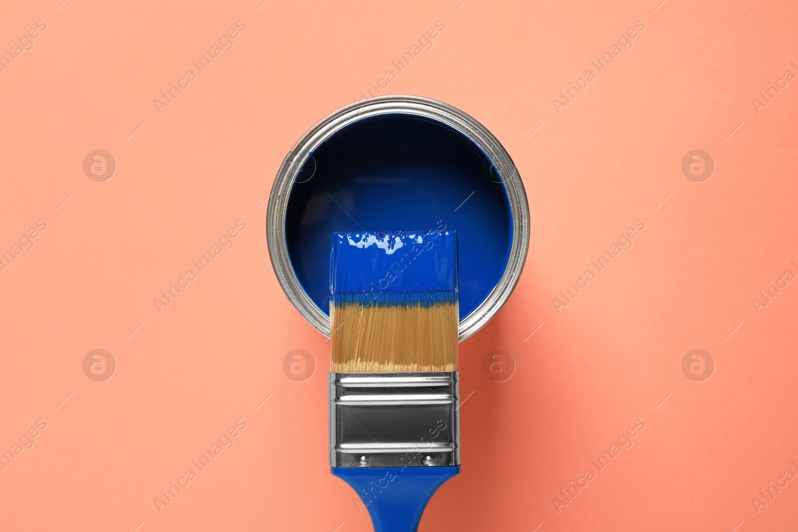 Photo of Can of paint and brush on orange background, top view. Color of the year 2020 (Classic blue)