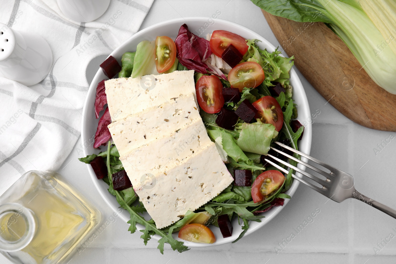 Photo of Tasty salad with tofu and vegetables served on white tiled table, flat lay