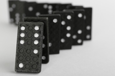 Photo of Black domino tiles falling on white background. Space for text