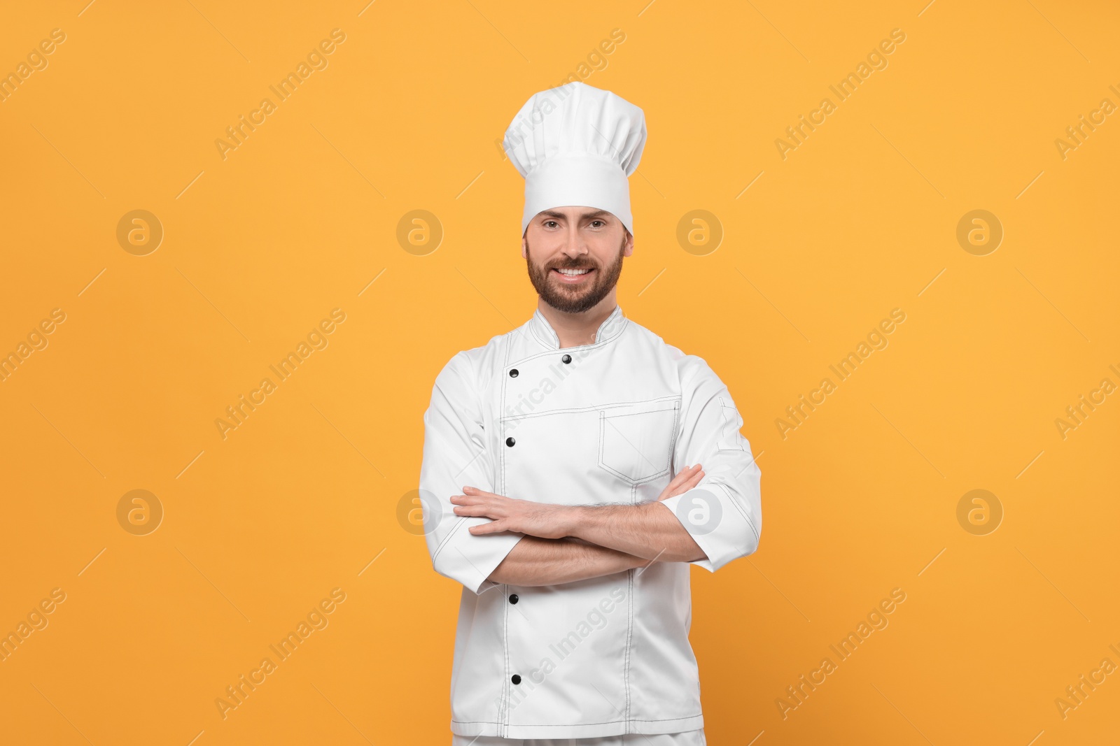 Photo of Smiling mature male chef on orange background