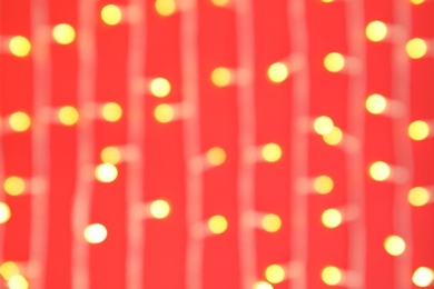 Photo of Blurred view of glowing Christmas lights on color background, top view