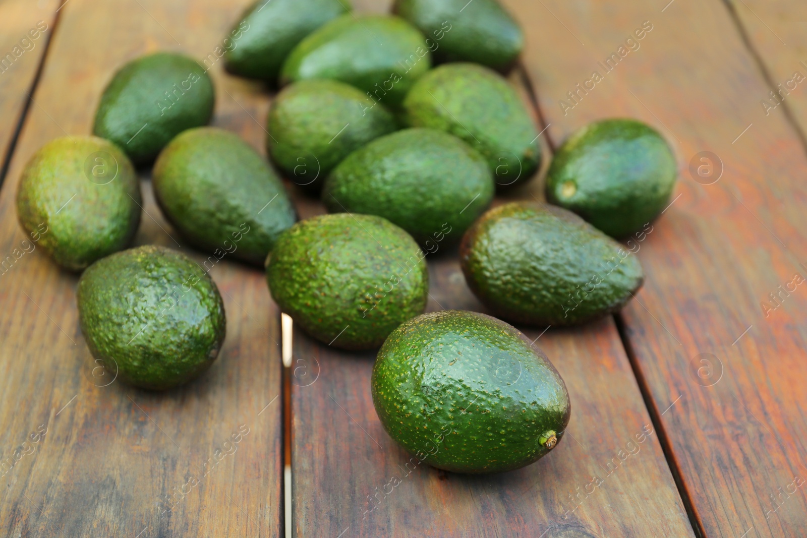 Photo of Tasty ripe avocados on wooden table outdoors
