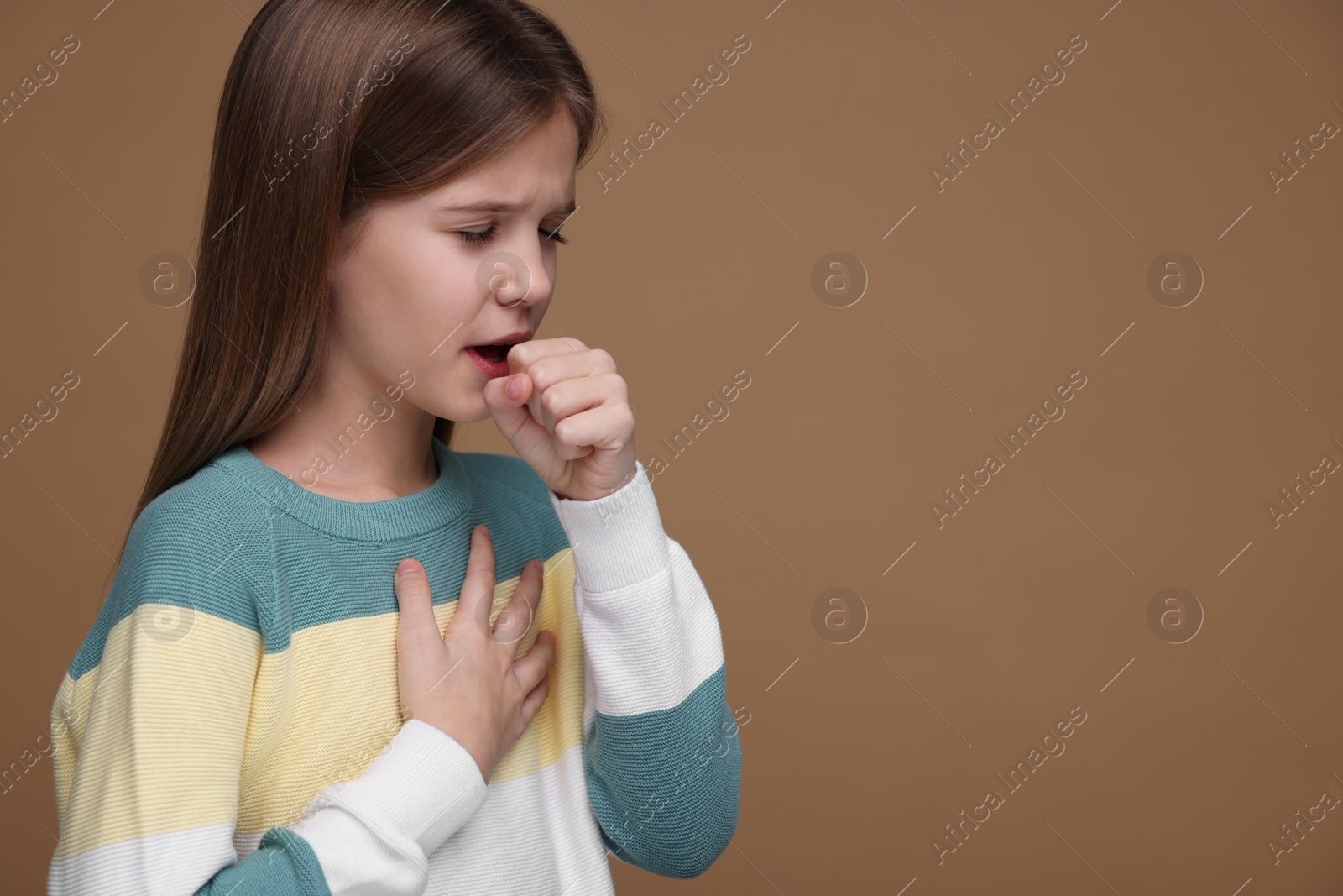 Photo of Sick girl coughing on brown background, space for text