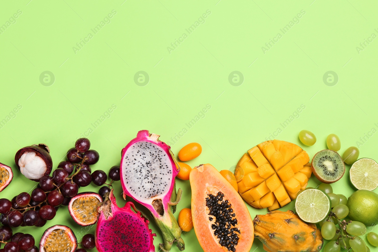 Photo of Many different delicious exotic fruits on green background, flat lay. Space for text