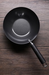 Photo of Empty iron wok on wooden table, top view. Chinese cookware