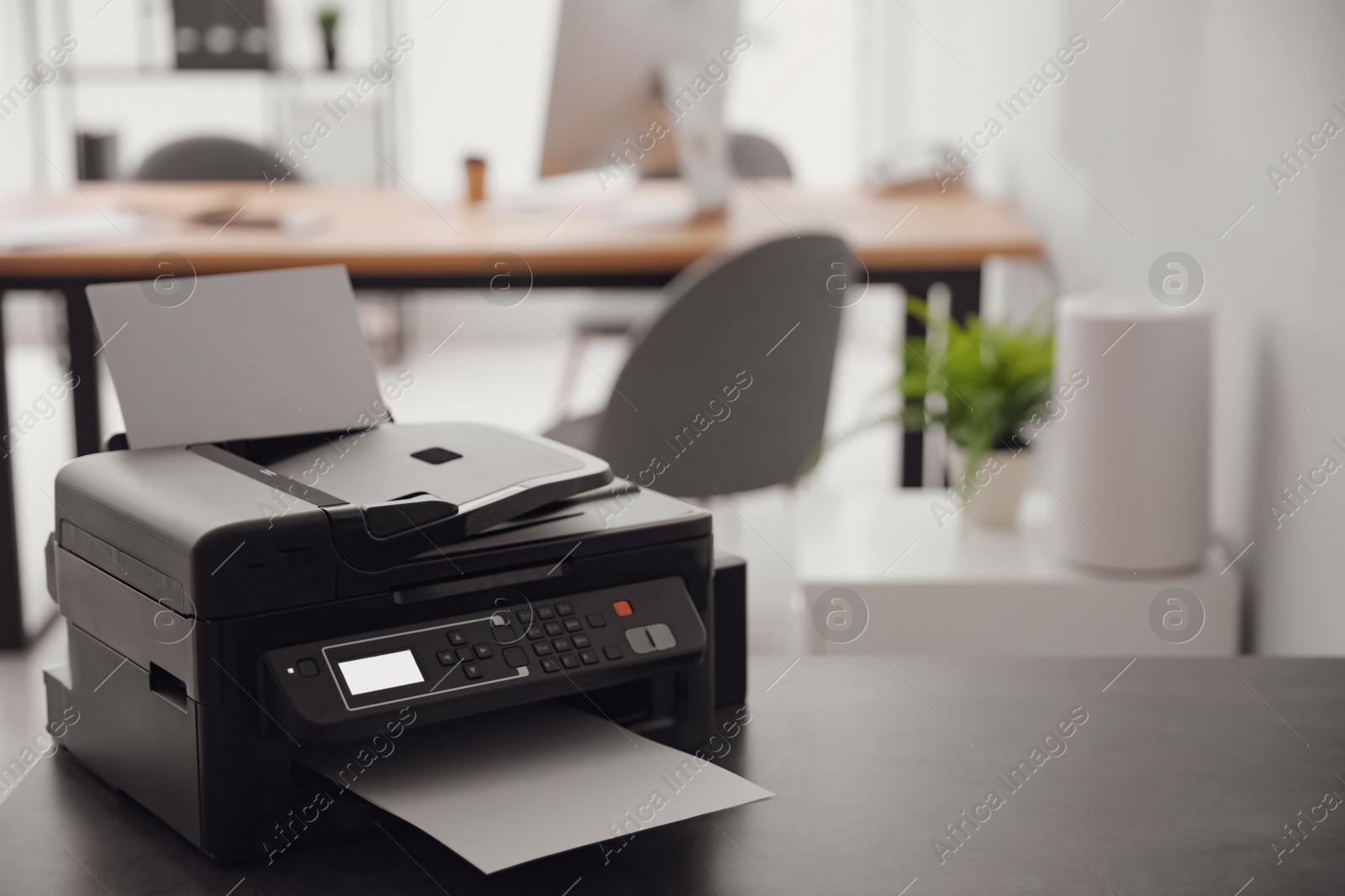 Photo of New modern printer on table in office. Space for text