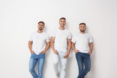 Group of young men in jeans on light background
