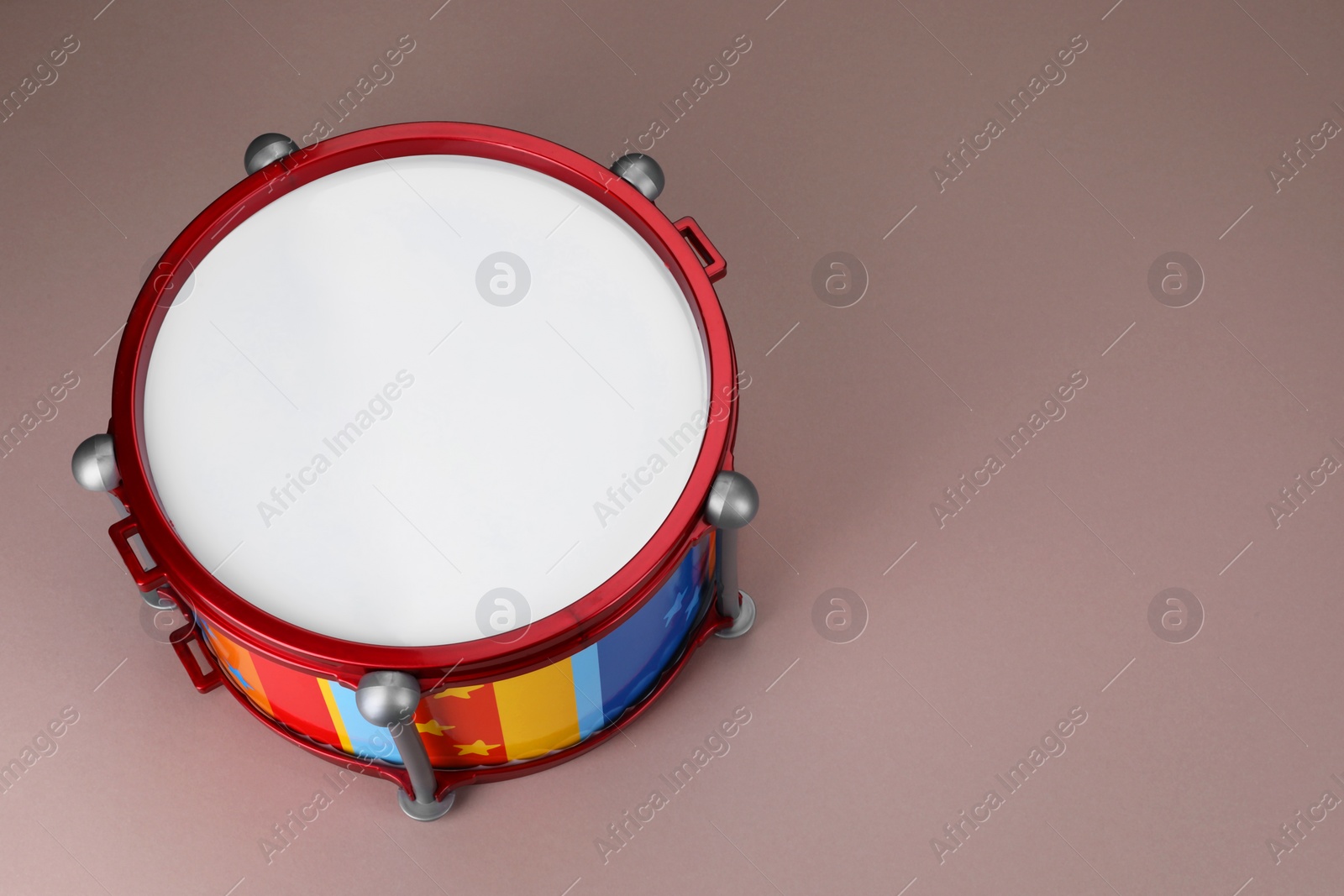Photo of Colorful drum on dusty rose background, above view with space for text. Percussion musical instrument