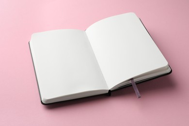 Photo of Open notebook with blank pages on light pink background