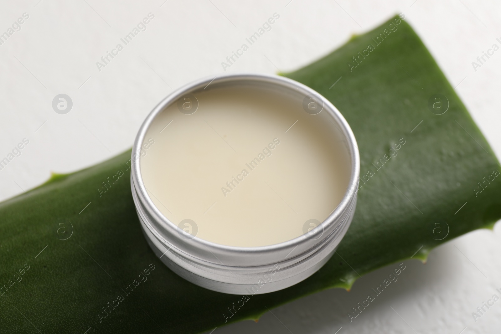 Photo of Lip balm and aloe vera plant on white background, closeup