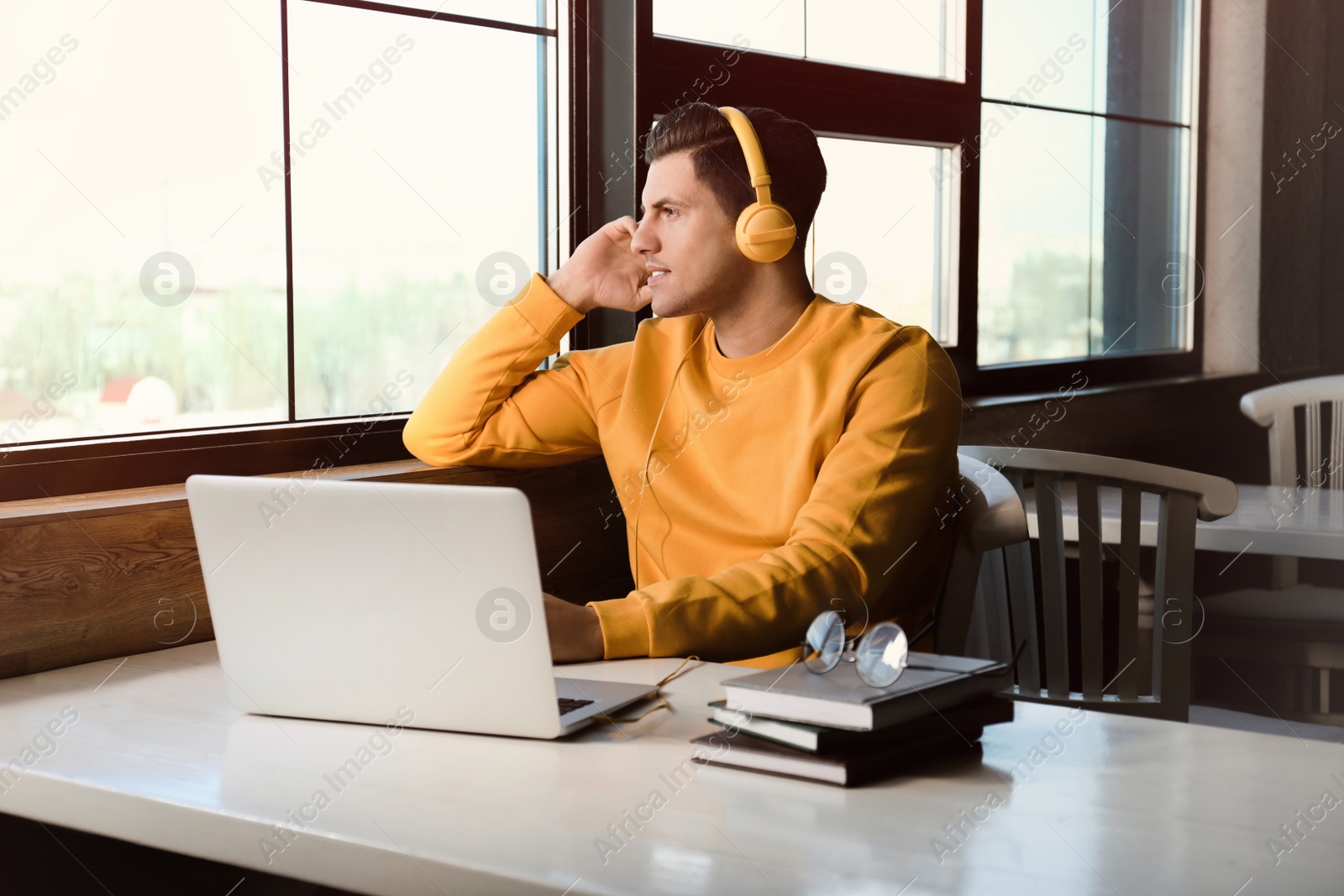 Photo of Man listening to audiobook at table in cafe