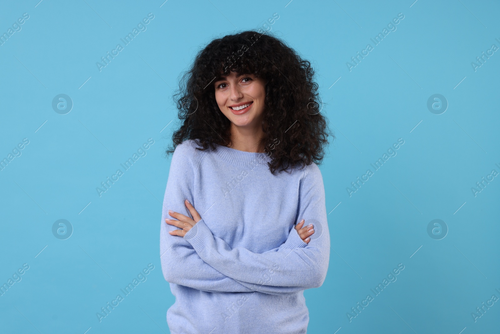 Photo of Happy young woman in stylish warm sweater on light blue background