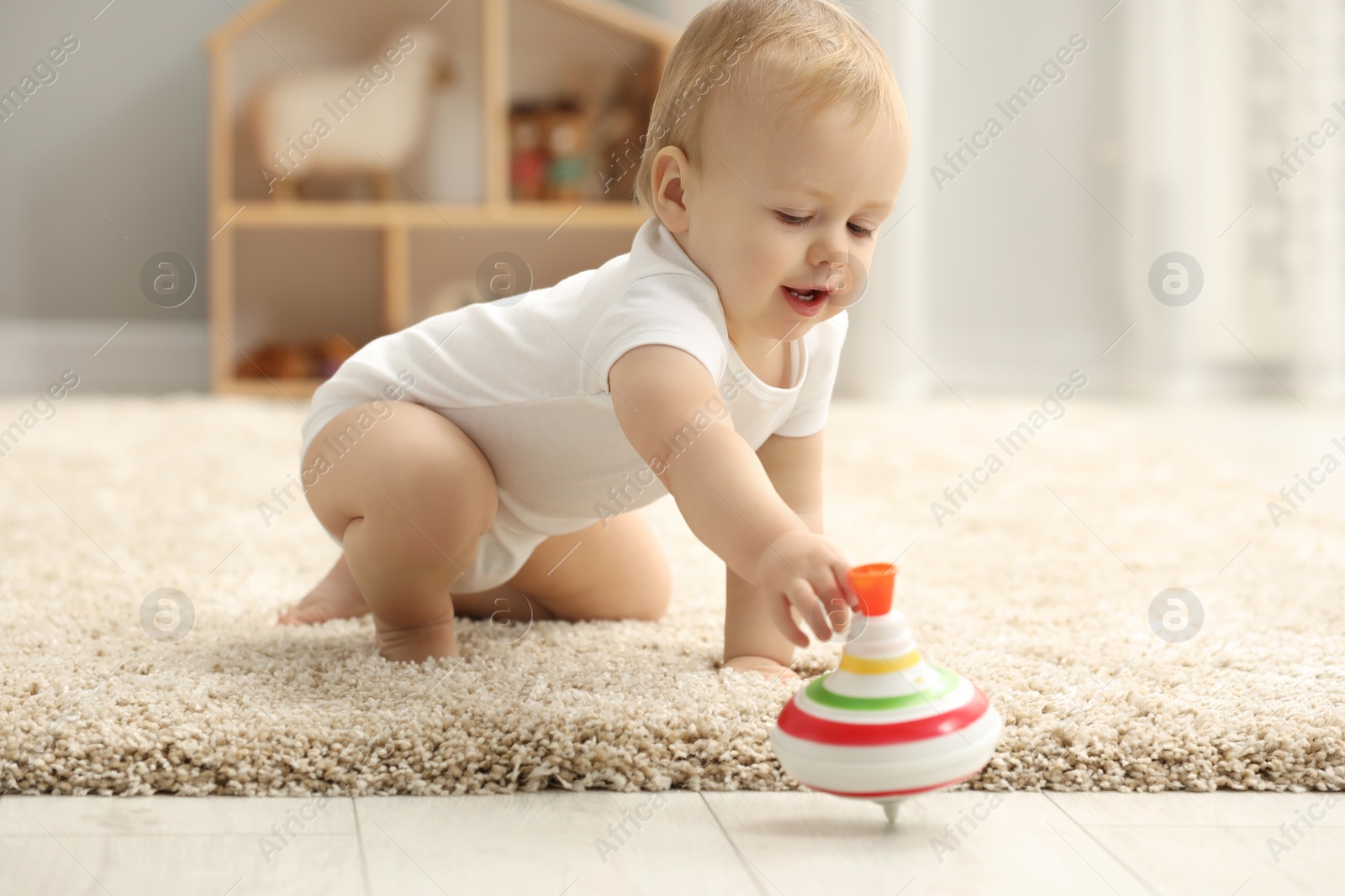 Photo of Children toys. Cute little boy playing with spinning top on rug at home