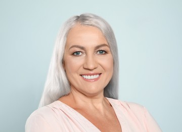 Portrait of smiling woman with ash hair color on light grey background