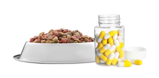 Image of Dry pet food in feeding bowl and bottle with vitamin pills on white background