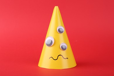 Photo of Monster made of yellow paper on red background. Halloween decoration