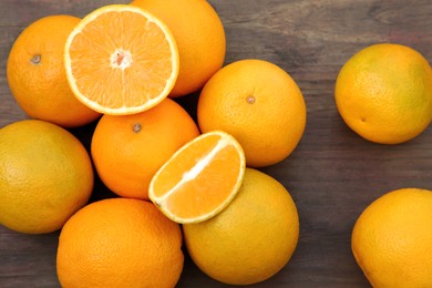 Many whole and cut oranges on wooden table, flat lay