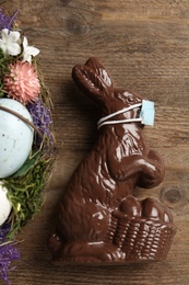 Photo of Chocolate bunny with protective mask on wooden table, top view. Easter holiday during COVID-19 quarantine