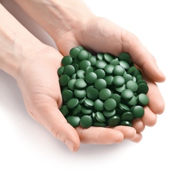 Photo of Woman holding heap of green spirulina pills on white background, top view