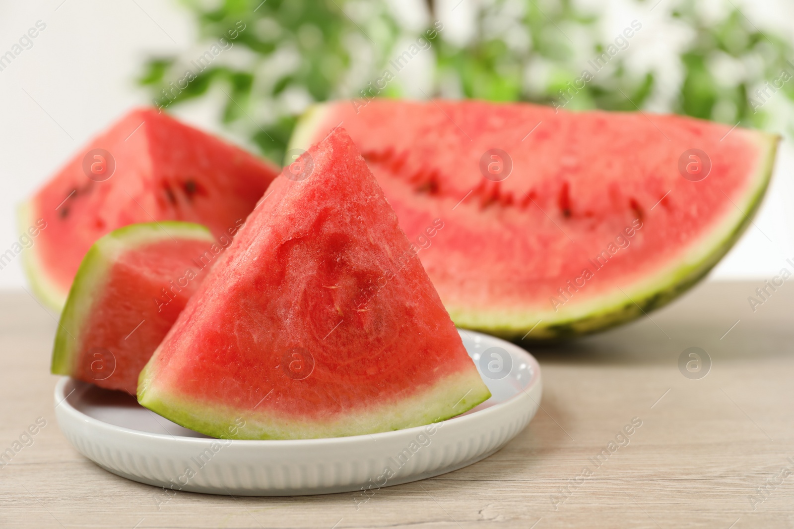 Photo of Slices of tasty ripe watermelon on light wooden table, closeup