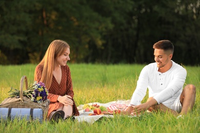 Photo of Young man and his girlfriend having picnic in park