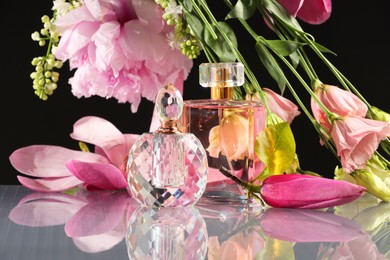 Luxury perfumes and floral decor on mirror surface against black background