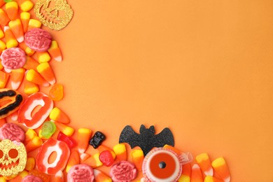 Photo of Delicious bright candies on orange background, flat lay with space for text. Halloween sweets