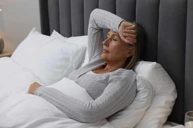 Menopause. Woman suffering from headache in bed indoors