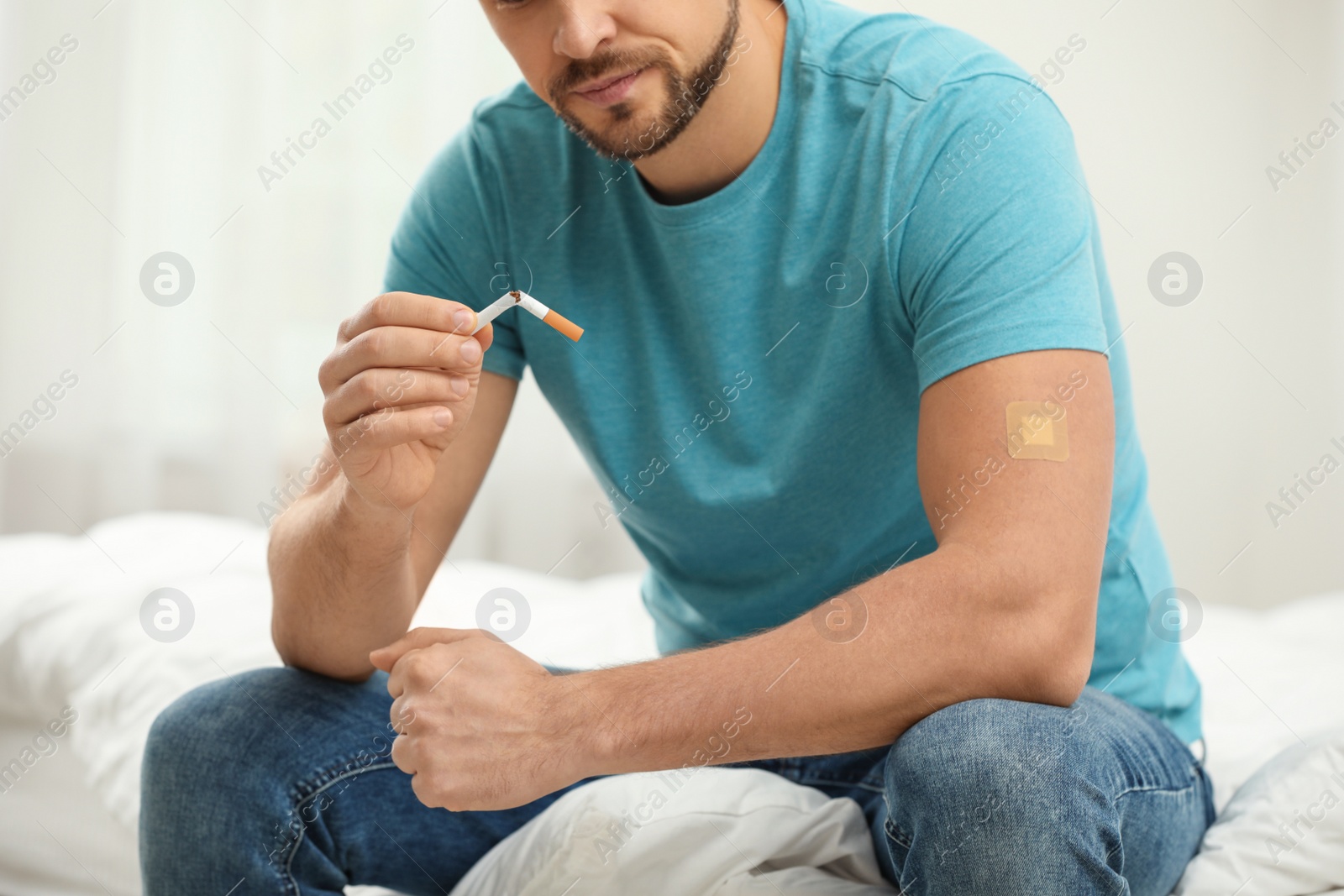 Photo of Man with nicotine patch and cigarette in bedroom, closeup