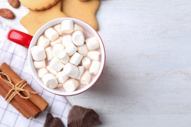 Flat lay composition of tasty cocoa with marshmallows on white wooden table. Space for text