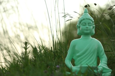 Photo of Decorative Buddha statue in green grass outdoors, space for text