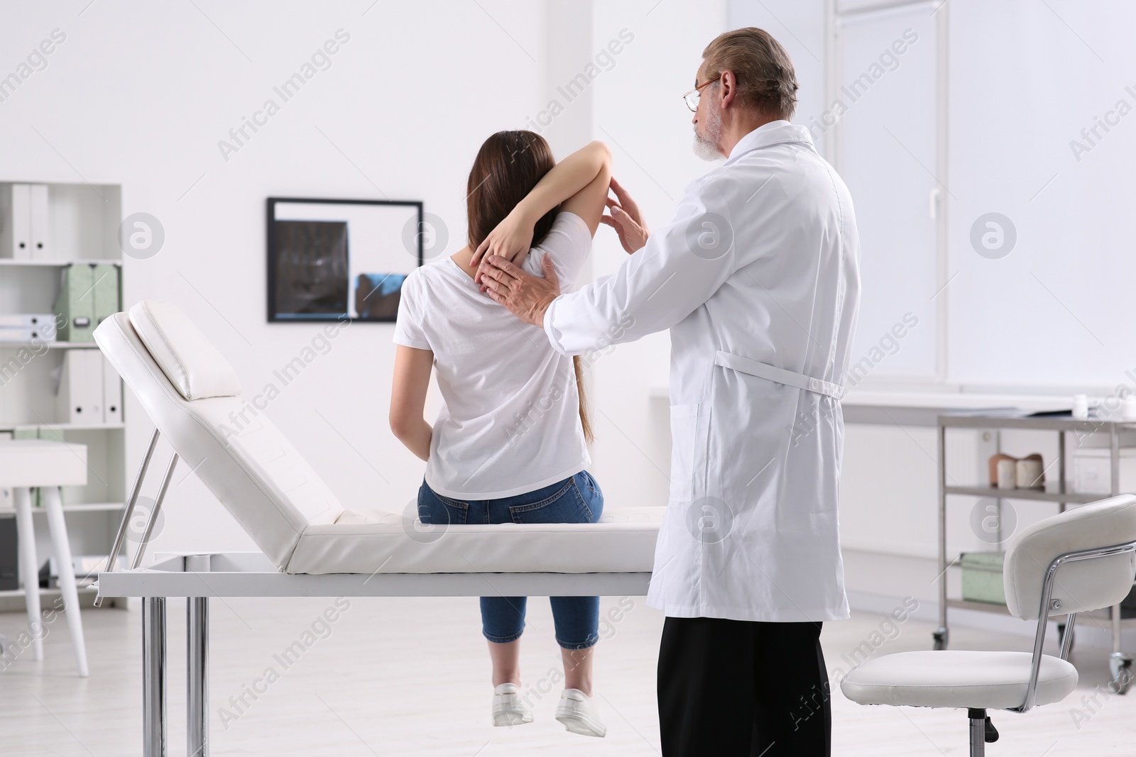 Photo of Professional orthopedist examining patient's shoulder in clinic