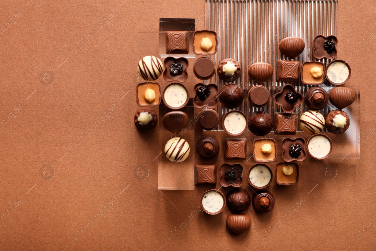 Photo of Heart made with delicious chocolate candies on brown background, top view