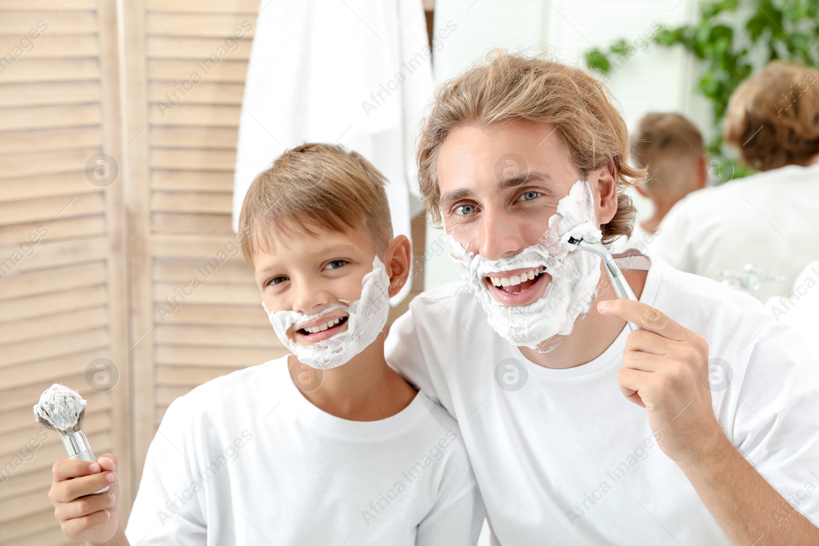 Photo of Father and son shaving together in bathroom