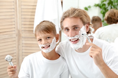 Photo of Father and son shaving together in bathroom